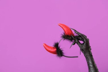 Mor arka planda kırmızı şeytan boynuzları olan cadının eli. Cadılar Bayramı