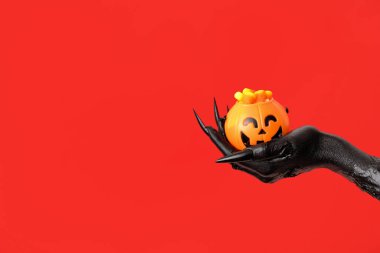 Cadıların kara eli ve kırmızı arka planda lezzetli mısır şekerleri. Cadılar Bayramı