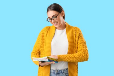 Açık mavi arkaplan üzerine kitapları olan genç bayan öğretmen