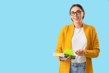 Açık mavi arkaplan üzerine kitapları olan genç bayan öğretmen