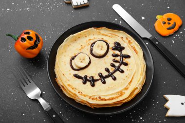 Üzerinde komik Cadılar Bayramı krepleri, çatal bıçak takımı ve dekorasyon olan tabaklar, yakın plan.