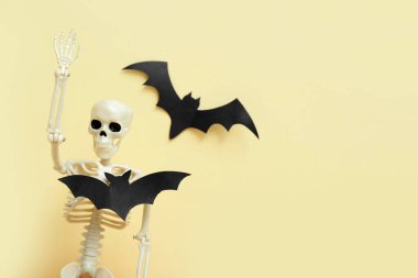 Cadılar Bayramı partisi için bej arka planda iskelet ve kağıt yarasalar