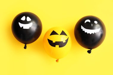 Sarı arka planda farklı komik Cadılar Bayramı balonları