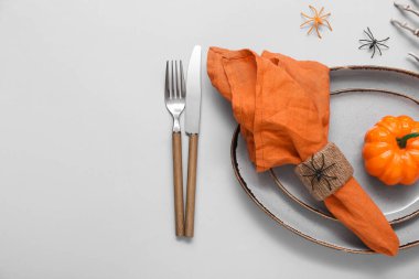 Cadılar Bayramı balkabağı ve gri arka planda örümceklerle şenlik masası.