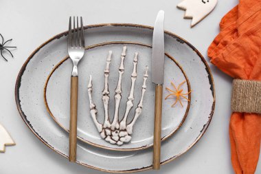 Cadılar Bayramı süslemeleri ve gri arka planda iskelet eli şenlik masası.