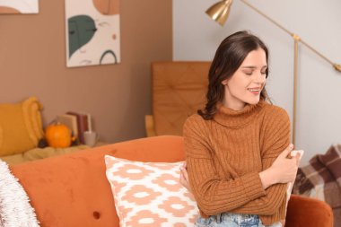 Mutlu genç bir kadın, sonbahar günü evde oturuyor.