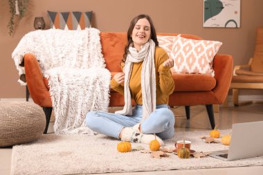 Sonbahar günü eşarplı genç bir kadın evde oturuyor.