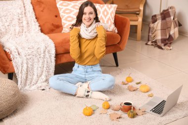 Sonbahar günü eşarplı genç bir kadın evde oturuyor.