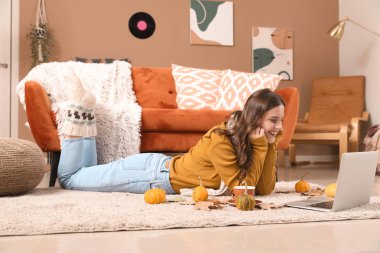 Sonbahar günü evde dizüstü bilgisayar kullanan genç bir kadın.