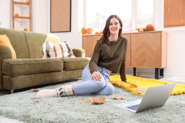 Sonbahar günü evde oturan genç bir kadın.