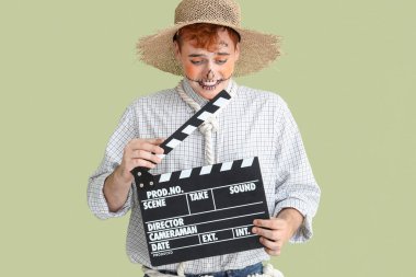 Cadılar Bayramı için yeşil arka planda el çırpmalı korkuluk gibi giyinmiş yakışıklı genç adam.