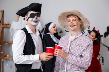 Cadılar Bayramı partisinde kostümlü erkek arkadaşlar içiyor.