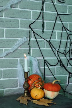 Cadılar Bayramı balkabaklarıyla yanan mum ve karanlık odada düşen yapraklar.