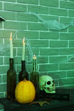 Cadılar Bayramı balkabağı, kafatası ve kitabı karanlık odada yanan mumlar.