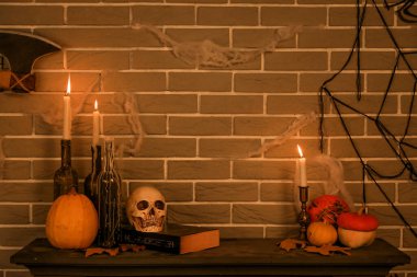 Karanlık odada şömine rafında Cadılar Bayramı dekoruyla mum yakmak.