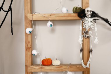 Wooden ladder with Halloween decor near light wall clipart