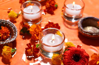 Turuncu arka planda suda kadife çiçekleriyle mum yakmak. Divaly kutlaması