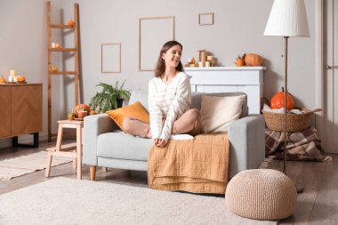 Evdeki kanepede oturan genç bir kadın.