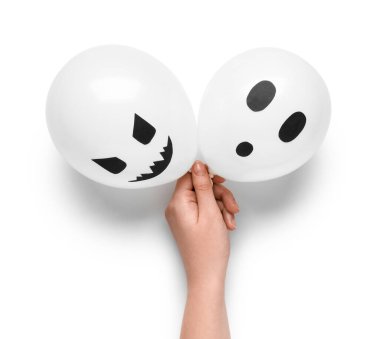 Beyaz arka planda komik Cadılar Bayramı balonları olan bir kadın eli.