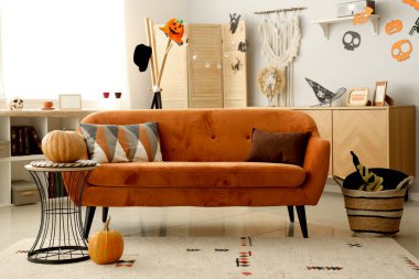 Cadılar Bayramı için kırmızı kanepe ve balkabaklarıyla dekore edilmiş oturma odasının içi.