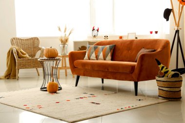 Cadılar Bayramı için kırmızı kanepe ve balkabaklarıyla dekore edilmiş oturma odasının içi.