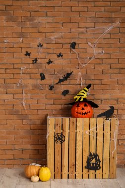 Odasında tuğla duvar olan Cadılar Bayramı balkabakları olan ahşap bir raf.