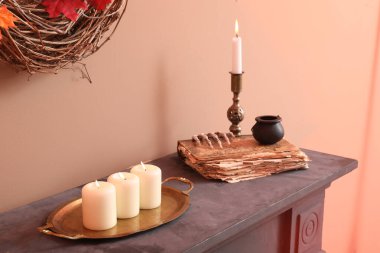 Burning candles with Halloween decor on mantelpiece in hall clipart