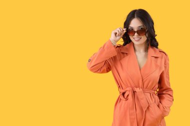 Sarı arka planda sonbahar elbiseli şık Asyalı kadın.