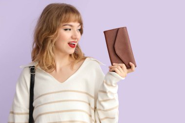 Leylak arka planda cüzdanı olan genç bir kadın.