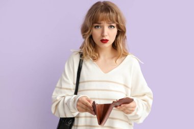 Leylak arka planında boş cüzdanı olan üzgün genç bir kadın.