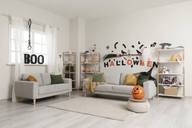 Cadılar Bayramı için dekore edilmiş oturma odasının içi kanepeler ve raf üniteleriyle dolu.