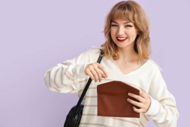 Leylak arka planda cüzdanı olan genç bir kadın.