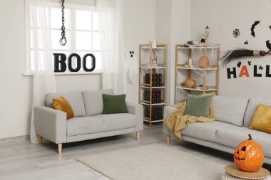 Cadılar Bayramı için dekore edilmiş oturma odasının içi kanepeler ve raf üniteleriyle dolu.