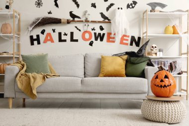 Cadılar Bayramı için dekore edilmiş oturma odasının içi kanepe ve raf üniteleriyle dolu.