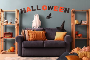 Cadılar Bayramı için dekore edilmiş oturma odasının içi kanepe ve raf üniteleriyle dolu.