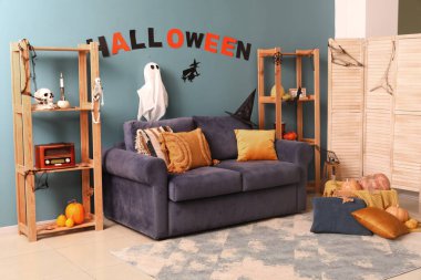 Cadılar Bayramı için dekore edilmiş oturma odasının içi kanepe ve raf üniteleriyle dolu.