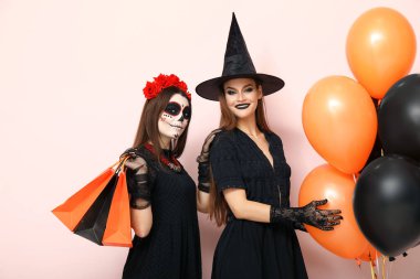 Cadılar Bayramı için giyinmiş genç kadınlar, alışveriş torbaları ve balonlarla aydınlık arka planda