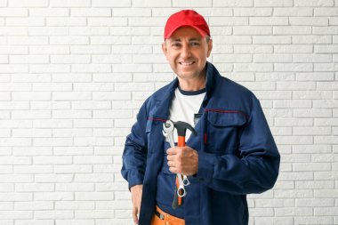 Beyaz tuğla arka planda aletleri olan erkek tamircinin portresi