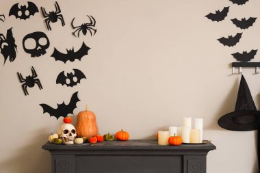 Kafatası ve şömine rafında mumlar olan Cadılar Bayramı balkabakları.