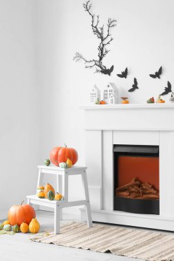 Cadılar Bayramı için dekore edilmiş oturma odasının içi şömine, balkabağı ve kağıt yarasalarla süslenmiş.