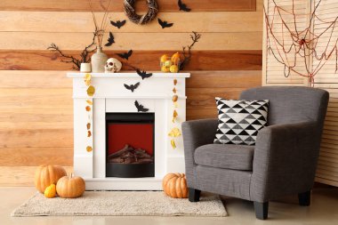 Cadılar Bayramı için dekore edilmiş oturma odasının içinde şömine ve koltuk var.