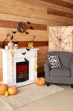 Cadılar Bayramı için dekore edilmiş oturma odasının içinde şömine ve koltuk var.