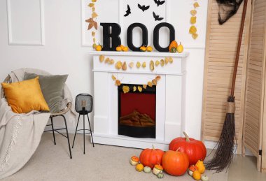 Cadılar Bayramı için dekore edilmiş oturma odasının içinde şömine ve koltuk var.