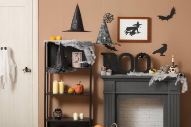 Cadılar Bayramı için dekore edilmiş oturma odasının içinde raf ünitesi ve şömine rafı var.