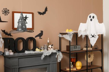 Cadılar Bayramı için dekore edilmiş oturma odasının içinde raf ünitesi ve şömine rafı var.