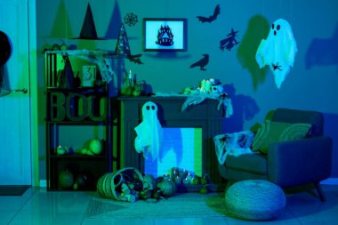 Cadılar Bayramı için dekore edilmiş karanlık oturma odasının içinde koltuk ve şömine rafı var.