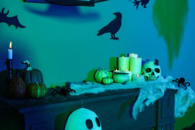 Kafatası yanan mumlar ve karanlık odada şömine rafında Cadılar Bayramı balkabakları