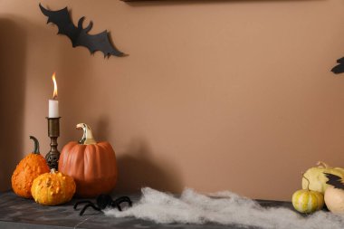 Şömine rafında yanan mum olan Cadılar Bayramı balkabakları.