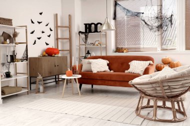 Cadılar Bayramı için dekore edilmiş oturma odasının içinde kırmızı kanepe ve koltuk var.