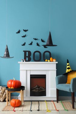 Cadılar Bayramı için dekore edilmiş oturma odasının içinde şömine ve koltuk var.